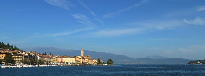 Trip Ukraine beliebte Urlaubsziele am Gardasee -  Mit einer Fläche von 370 km² ist der Gardasee der größte See Italiens. Es liegt am Fuße der Alpen und erstreckt sich über drei Staaten: Lombardei, Venetien und Trentino. Die maximale Tiefe des Sees beträgt 346 m, er hat eine längliche Form und sein nördliches Ende ist sehr schmal. Dort ist der See von den Bergen der Gruppo di Baldo umgeben. Du trittst aus deinem gemütlichen Hotelzimmer und es begrüßt dich die warme italienische Sonne. Du blickst auf den atemberaubenden Gardasee, der in zahlreichen Blautönen schimmert - von tiefem Dunkelblau bis zu funkelndem Türkis. Majestätische Berge umgeben dich, während die Brise sanft deine Haut streichelt und der Duft von blühenden Zitronenbäumen deine Nase kitzelt. Du schlenderst die malerischen, engen Gassen entlang, vorbei an farbenfrohen, blumengeschmückten Häusern. Vereinzelt unterbricht das fröhliche Lachen der Einheimischen die friedvolle Stille. Du fühlst dich wie in einem Traum, der nicht enden will. Jeder Schritt führt dich zu neuen Entdeckungen und Abenteuern. Du probierst die köstliche italienische Küche mit ihren frischen Zutaten und verführerischen Aromen. Die Sonne geht langsam unter und taucht den Himmel in ein leuchtendes Orange-rot - ein spektakulärer Anblick.